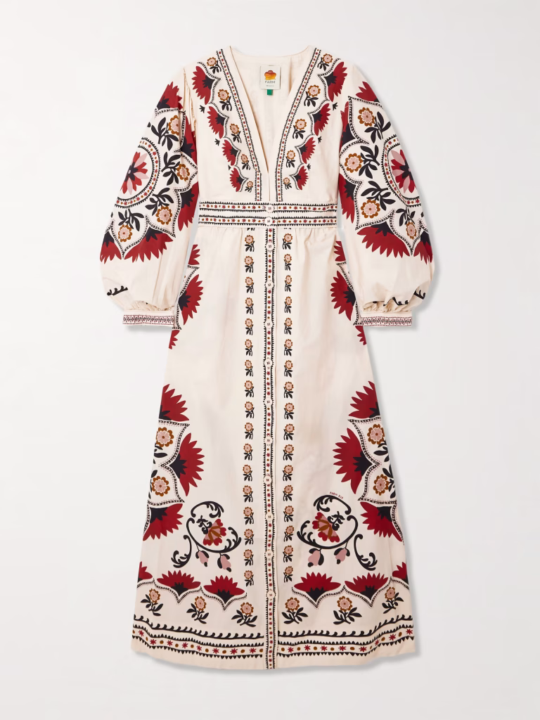 A cream-colored, long-sleeve maxi dress with a V-neckline and intricate, bold floral and geometric embroidery in red, black, and tan along the sleeves, bodice, and hem. The dress has a fitted waist and wide, gathered sleeves with patterned cuffs.
