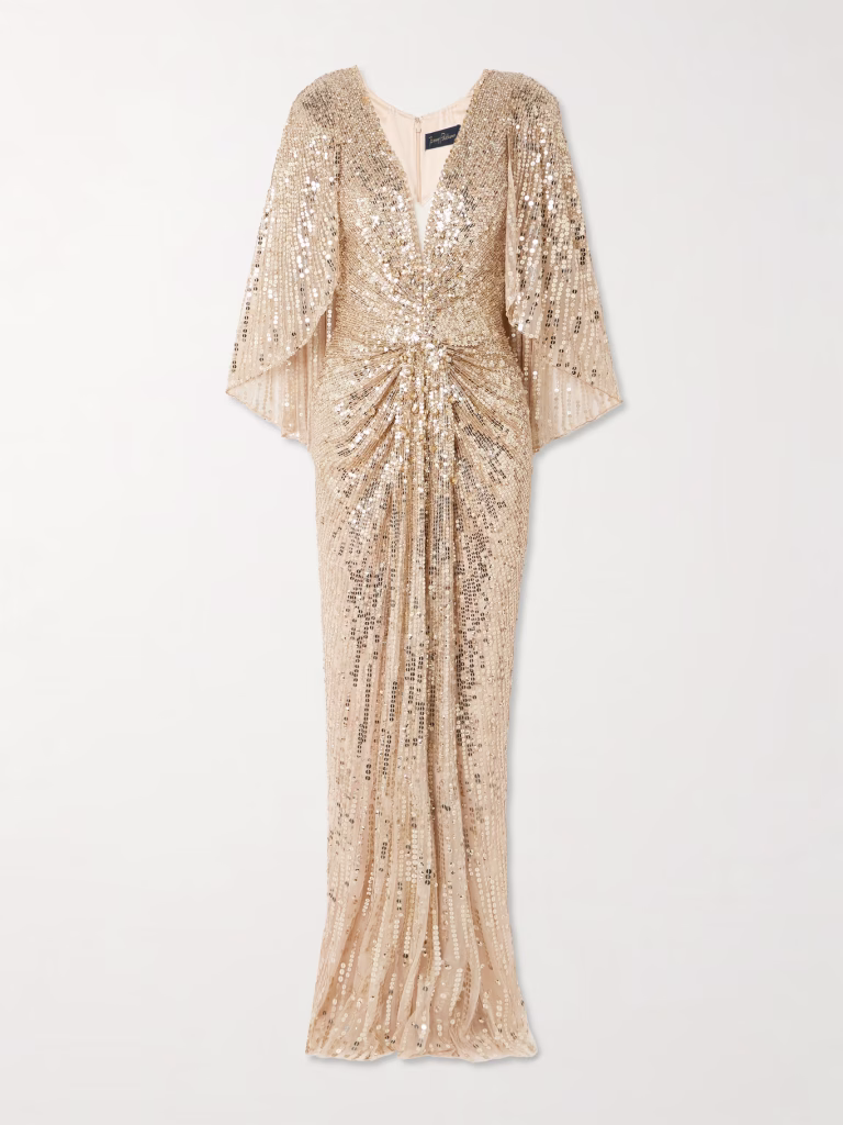 A floor-length, champagne-colored gown covered in sparkling sequins. The dress features a deep V-neckline, wide draped sleeves, and a ruched waist detail—perfect for glamorous Christmas styling. The fabric drapes smoothly to the hem.