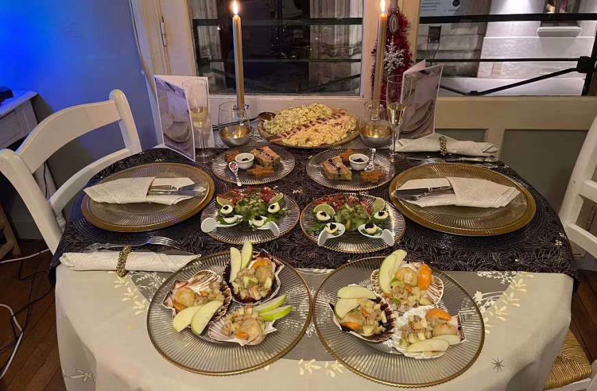 A candlelit dinner table set for four with gold-rimmed plates, seafood appetizers, deviled eggs as a festive starter, leafy greens, and wine glasses. Two lit candles, luxury decorations, and elegant dishes create a cozy yet artistic ambiance.